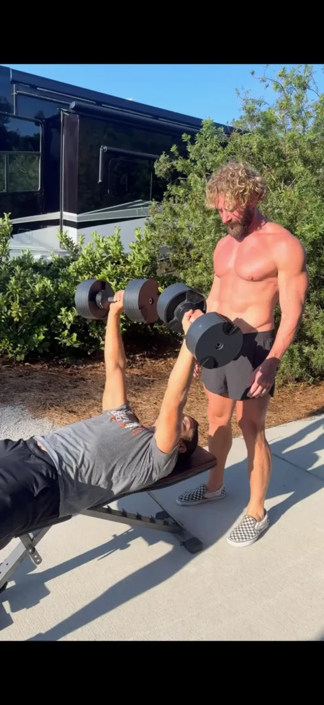 drew sinclair standing behind a weight bench as he coaches a client